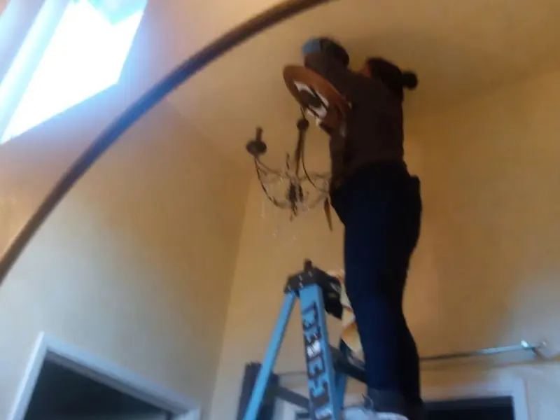 Electrician installing a chandelier in a Sharon Hill residence